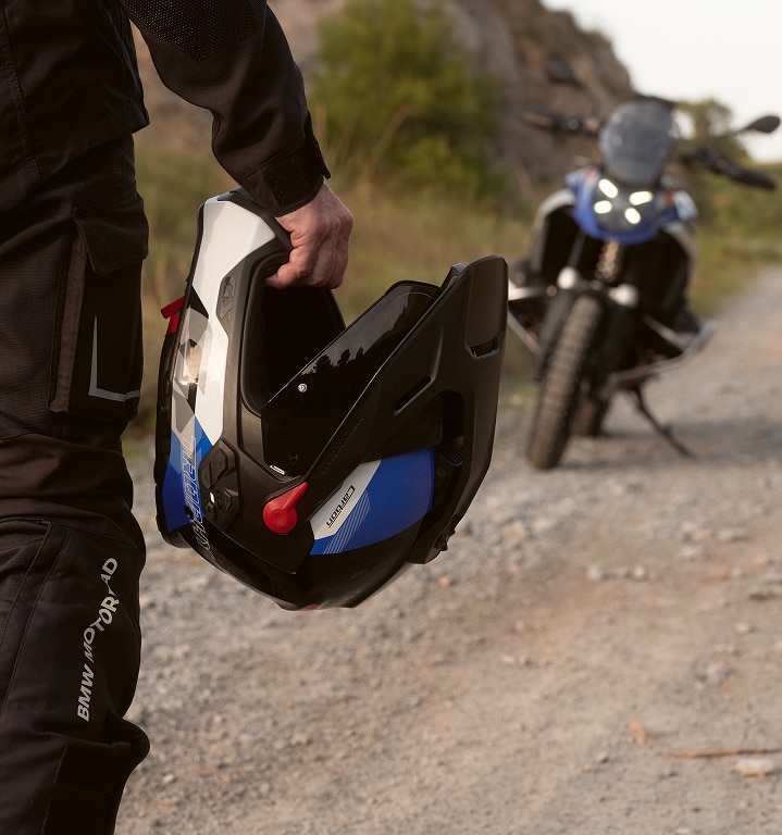 Osoba drží v ruce motocyklovou helmu.